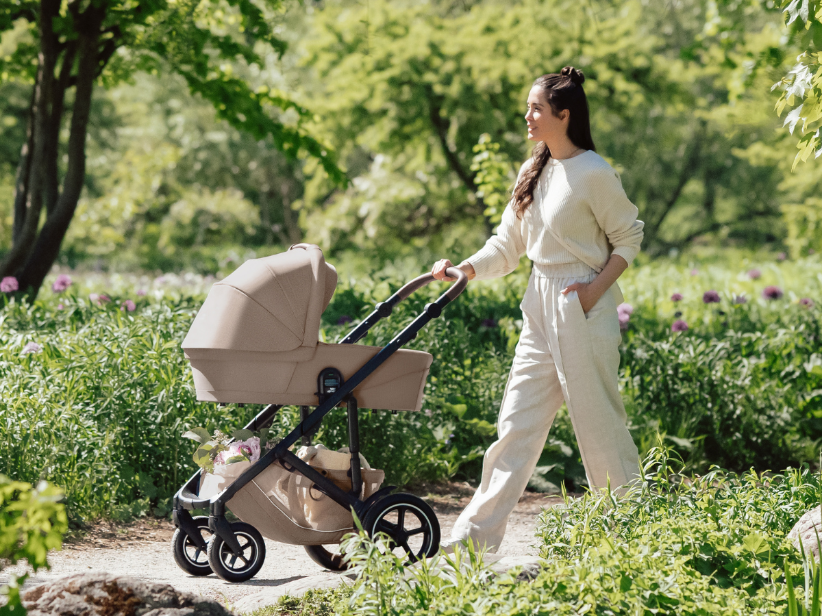Britax Römer SMILE 5Z All-Terrain-Kinderwagen mit Babywanne bei einem Familienspaziergang durch einen Park